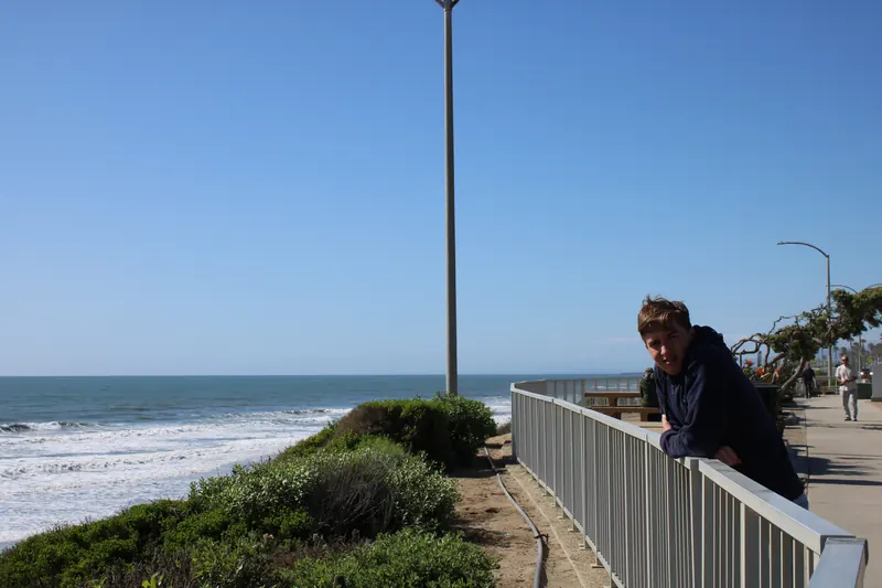 Josiah leaning on a railing above the beach